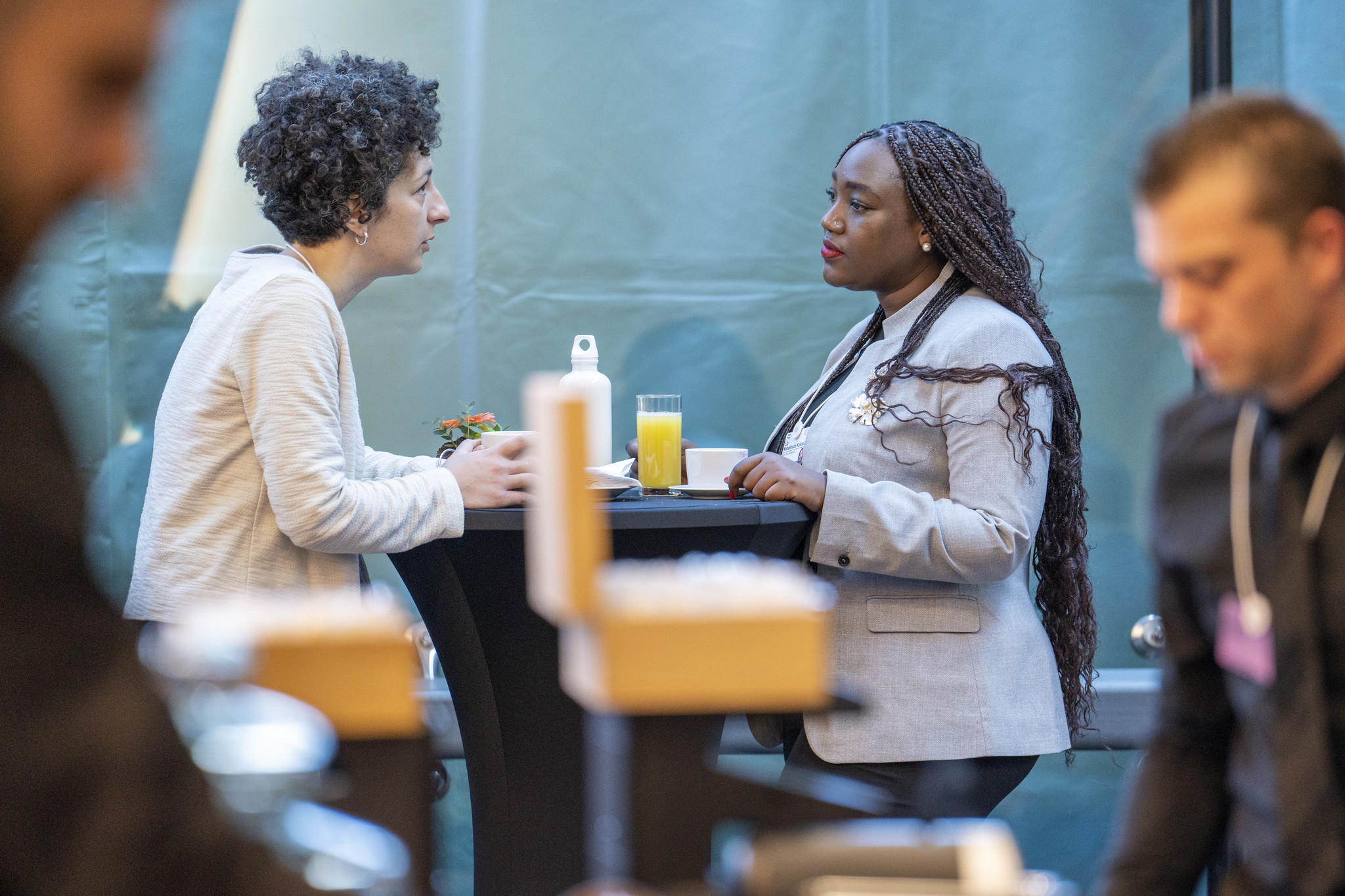 Two people sitting at a table with drinks talking