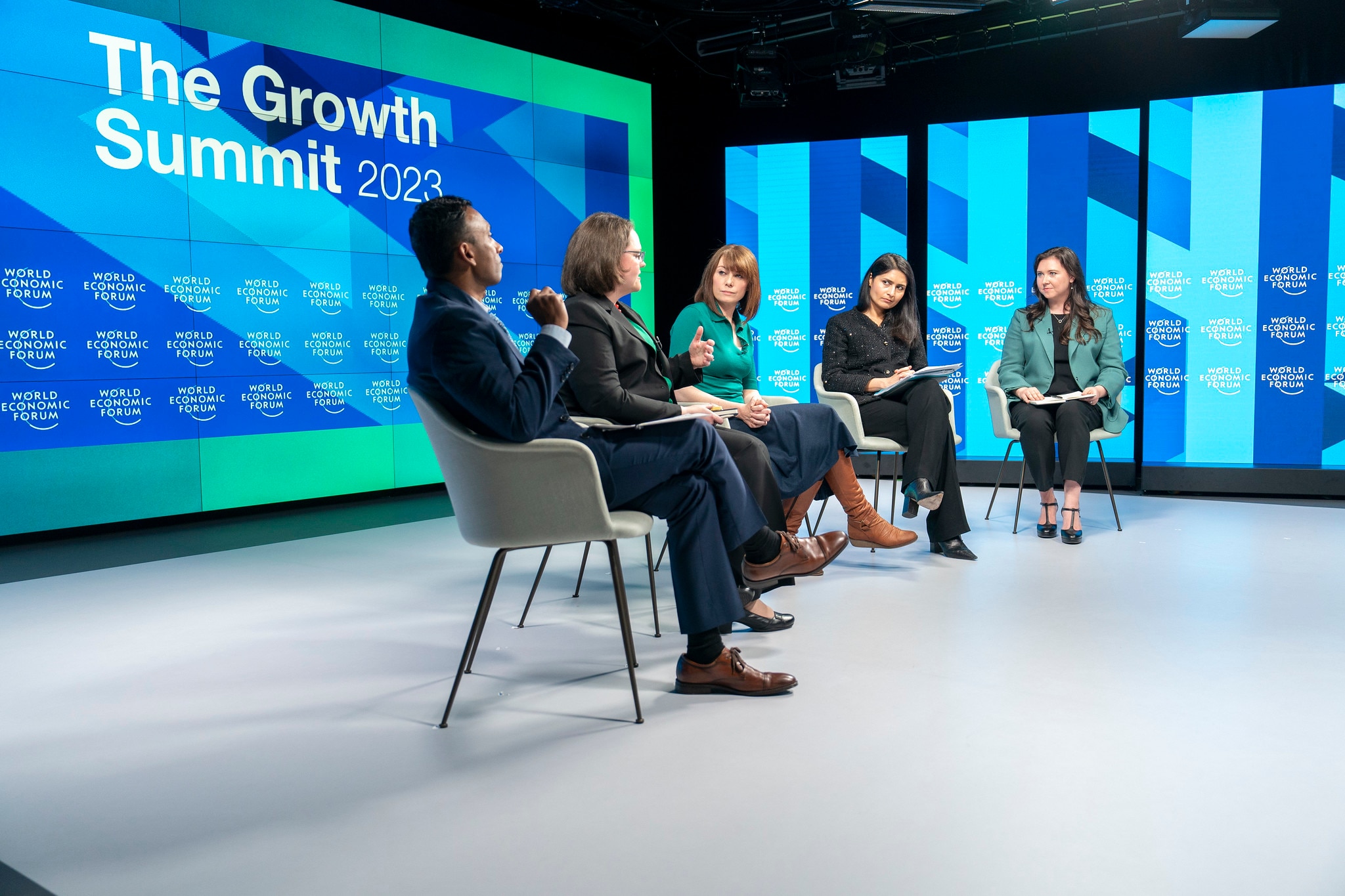 A group of people sitting in chairs on stage in discussion